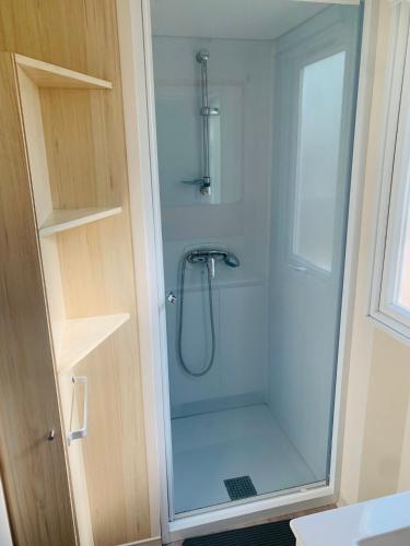 une douche avec une porte vitrée dans une salle de bain dans l'établissement Mobil-home, à Agde