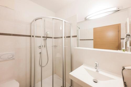 a white bathroom with a shower and a sink at Residence Aqualis in Marlengo