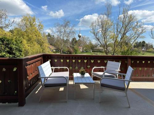 three white chairs and a table on a balcony at Kruna Palića in Palić