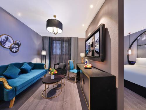 a hotel room with a blue couch and a bed at 上海五角场桔子水晶酒店 in Shanghai