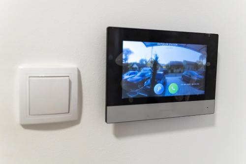 a tv attached to a wall with a lightswitch at Lana Lux 19 in Subotica