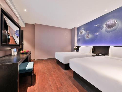 a hotel room with two beds and a flat screen tv at 上海五角场桔子水晶酒店 in Shanghai