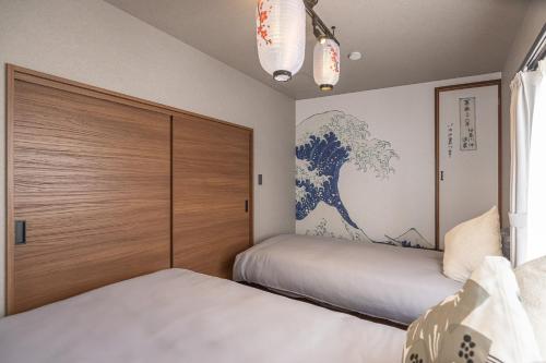 a bedroom with two beds and a painting on the wall at Kstyle Apartments UNO in Tamano