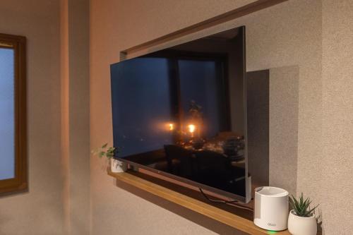 a television on a wall in a living room at Kstyle Apartments UNO in Tamano