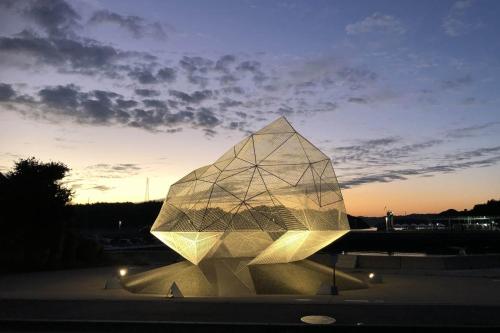 a glass pyramid with a sunset in the background at Kstyle Apartments UNO in Tamano