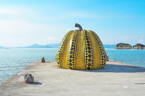 a large yellow sculpture of a pineapple sitting on a pier at Kstyle Apartments UNO in Tamano