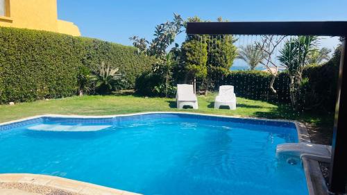 a swimming pool with two white chairs next to it at Villa Private pool cancun El Ain El Sokhna 63 in Ain Sokhna