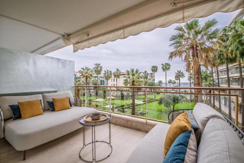 Il comprend un salon avec un canapé et un balcon avec des palmiers. dans l'établissement Mondrian By Terrys Homes, à Cannes