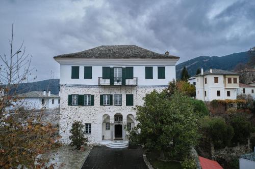 a large white house with green shutters on it at Despotiko in Portariá