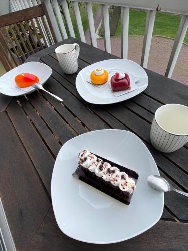 un morceau de gâteau sur des assiettes sur une table en bois dans l'établissement Logement avec balcon, à Ouistreham