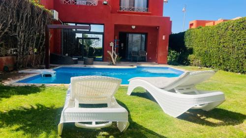 two chairs and a swimming pool in front of a house at Villa Private pool cancun El Ain El Sokhna 63 in Ain Sokhna