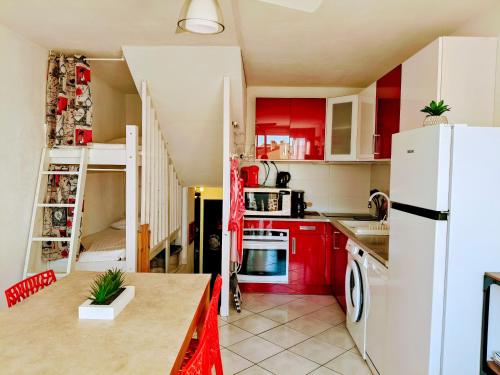 une cuisine avec des armoires rouges et un réfrigérateur blanc dans l'établissement Appartement T2 Duplex 4 P 35m2 avec parking, proche mer, au Grau-du-Roi