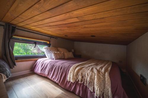 a bed in a small room with a wooden ceiling at Le Petit Haras de Valmont in Valmont