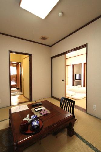 a room with a wooden table and a room with a bedroom at ひらゆの森別邸湯う香三蔵庵 in Takayama
