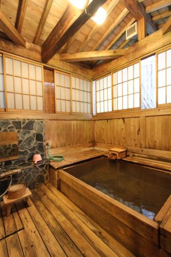 an indoor hot tub in a wooden house with windows at ひらゆの森別邸湯う香三蔵庵 in Takayama