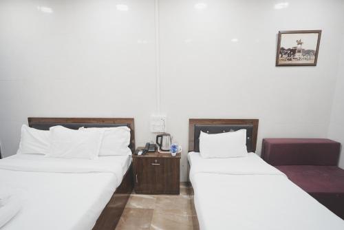 two beds sitting next to each other in a room at Hotel Jupiter Residency in Mumbai
