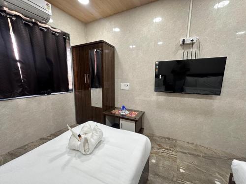 a room with a bed and a tv on a wall at Hotel Jupiter Residency in Mumbai