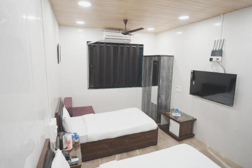 a room with a bed and a flat screen tv at Hotel Jupiter Residency in Mumbai