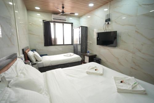 a hotel room with two beds and a tv at Hotel Jupiter Residency in Mumbai