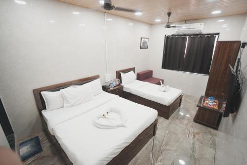 a hotel room with two beds and a chair at Hotel Jupiter Residency in Mumbai