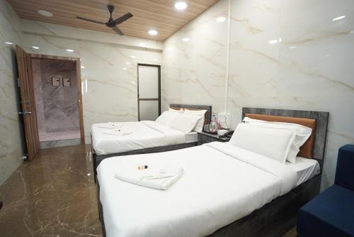 two beds in a hotel room with white sheets at Hotel Jupiter Residency in Mumbai