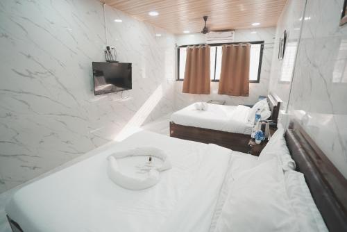 a small white bathroom with a bed and a tv at Hotel Jupiter Residency in Mumbai
