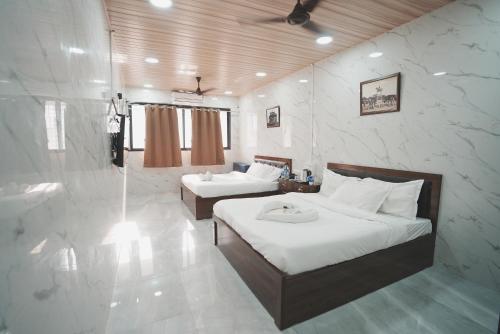 a bedroom with two beds and a shower in it at Hotel Jupiter Residency in Mumbai