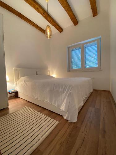 a bedroom with a white bed and two windows at Sweet holiday house in Veli Iž