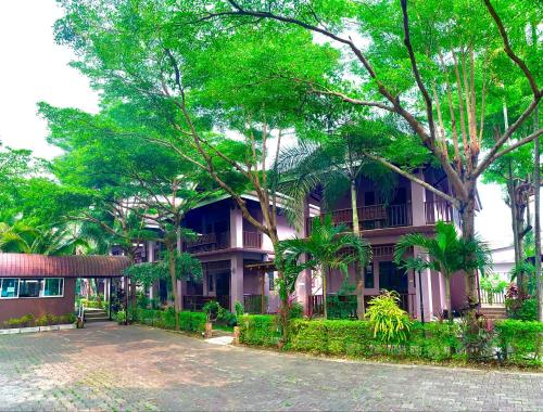 a pink building with trees in front of it at Baan Soontree Resort in Chiang Rai
