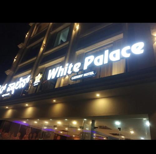 a white palace sign on the side of a building at Hotel White Palace in Belagula