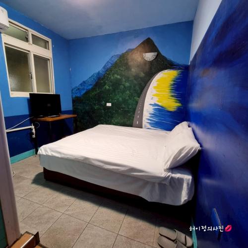 a bedroom with a bed with a painting on the wall at 清芳民宿 Delicateperfume Hotel 瑞芳車站-九份 平溪 Juifen Pingxi in Ruifang