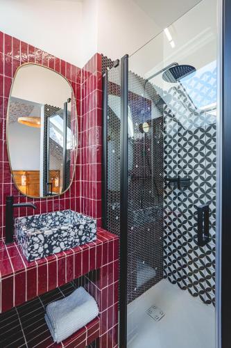 La salle de bains est pourvue de carrelage rouge, d'un lavabo et d'un miroir. dans l'établissement La Maison D'Ambre - Jacuzzi - Sauna- Clim, à Saumur