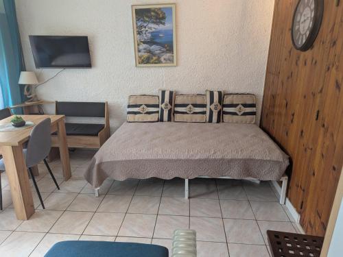 - une chambre avec un lit, une table et une horloge dans l'établissement BELLE VUE sur MER au CALME, à Argelès-sur-Mer