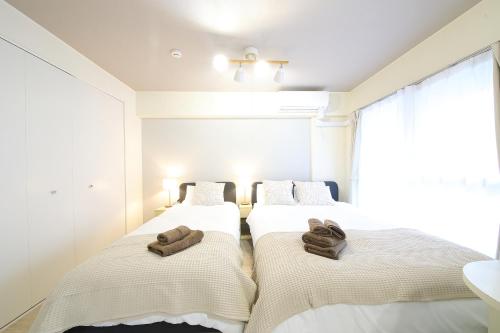 two beds in a room with towels on them at ノーザンヒルズ南6条 in Sapporo