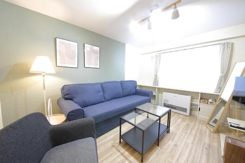 a living room with a blue couch and a tv at ノーザンヒルズ南6条 in Sapporo