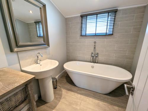a bathroom with a white tub and a sink at 1 or 2 bedroom Hot tub Lodges in North Walsham