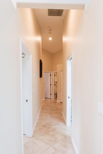 a hallway with white walls and tile floors at Golden Sands Emerald - Florida's Best - ALL Private Beachfront Estate with TENNIS-PICKLEBALL Court, Pool, Spa in Indialantic