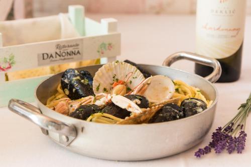 a bowl of pasta with mussels and a bottle of wine at Heritage Hotel Chersin in Fažana