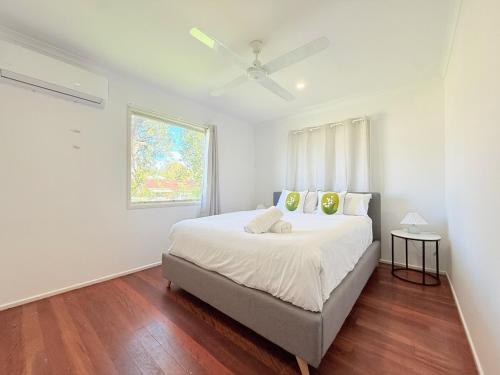 a white bedroom with a bed and a window at Family Comfort Modern 3BR Retreat in Brisbane