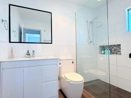 a white bathroom with a toilet and a shower at Family Comfort Modern 3BR Retreat in Brisbane