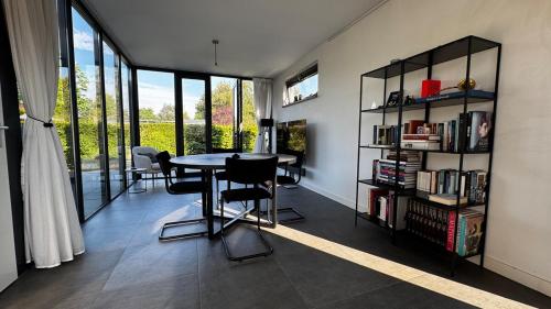 a dining room with a table and a book shelf at Modern bungalow with cinema in Ermelo