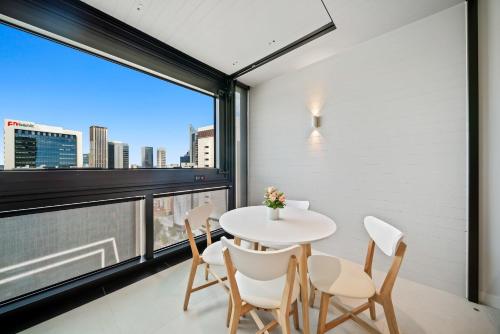 a table and chairs in a room with a large window at Luxury Perth CBD Apartment with Pool & Gym - Sleeps 3 in Perth