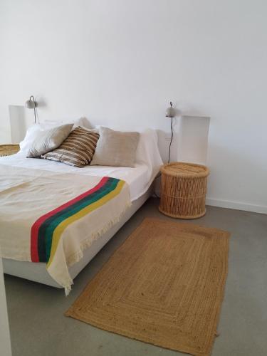 ein Schlafzimmer mit einem Bett mit einer Regenbogendecke und einem Teppich in der Unterkunft Sesmarias in Vila Real de Santo António