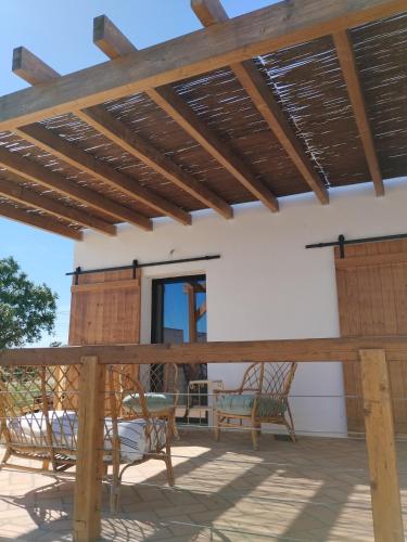 eine Terrasse mit Stühlen und einer hölzernen Pergola in der Unterkunft Sesmarias in Vila Real de Santo António