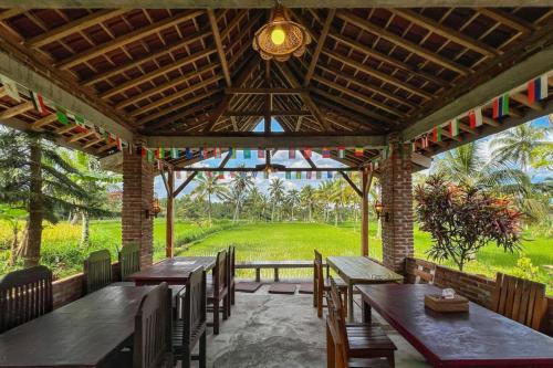a patio with wooden tables and chairs and a green field at Tereng Wilis bungalows in Tetebatu