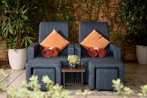 two blue chairs with pillows and a table with flowers at Hoi An Odyssey Hotel & Spa in Hoi An