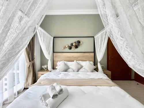 een slaapkamer met een groot bed met witte gordijnen bij Haven On The Lake in Dubai