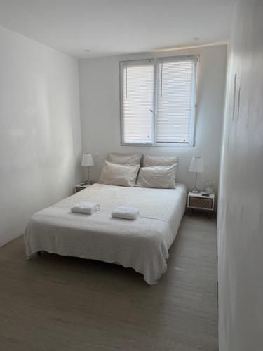 une chambre blanche avec un lit et deux fenêtres dans l'établissement Location proche de toute commodités à 1 minute du tramway et à 9 min de centre ville et parking gratuit dans résidence privée, à Nice