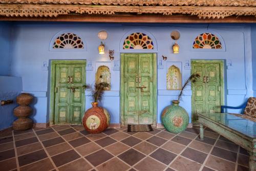 a room with green doors and vases on the wall at Castle View Haveli in Jodhpur