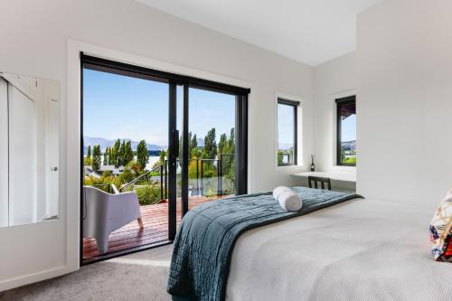 Un dormitorio con una cama grande y un balcón. en The Lookout - Lake Views, en Wanaka